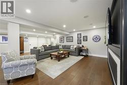 Spacious recreation area featuring wood-finish flooring, recessed lighting, and built-in ceiling speakers - 