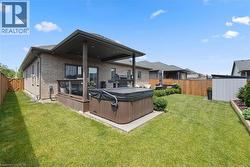 Spacious backyard featuring a covered deck, built-in hot tub, and a manicured lawn - 