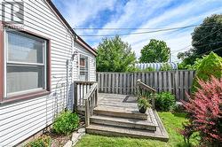 Wood deck with steps leading to a side entry, surrounded by a manicured lawn and mature privacy fencing - 