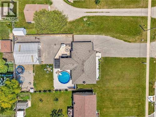Expansive property featuring a circular above-ground pool, a paved patio with an inset decorative compass design, a large paved driveway, a detached metal structure, and a secondary paved area - 192 Myers Road, Cambridge, ON 