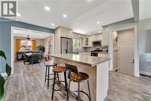Kitchen featuring a central island with a stone countertop, light-toned cabinetry, stainless steel appliances, and wood-finish flooring - 192 Myers Road, Cambridge, ON 