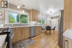 Light-filled kitchen with natural wood cabinetry, light countertops, and stainless steel appliances - 