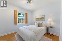 Bright room featuring wood-finish flooring, a window with wood louvered shutters, and a track light fixture - 