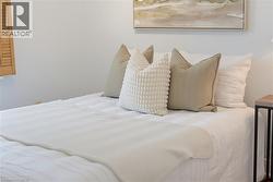 Light-filled room featuring white walls, wood window shutters, and a wall-mounted abstract art piece - 