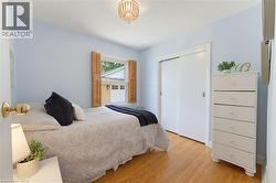 Bedroom with wood-finish flooring, light blue walls, and a beaded chandelier - 