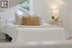 Bright bedroom featuring a single window, light-colored walls, and wood-finish flooring - 