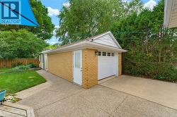 Detached brick garage with a white overhead door and service entrance - 