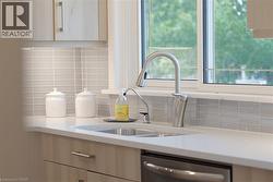 Contemporary kitchen featuring light wood-finish cabinetry, a white countertop, and a stainless steel gooseneck faucet - 