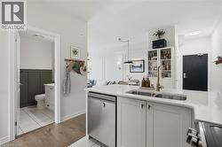 Modern kitchen island with a double basin sink, brushed gold faucet, white cabinetry, and a built-in stainless steel dishwasher - 