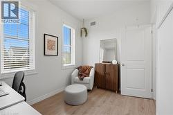 Bright room featuring two large windows with white blinds, wood-finish flooring, white baseboards, and a solid white interior door - 