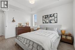Bright bedroom featuring light wood-finish flooring, white walls, and a window with blinds - 