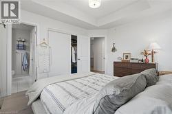 Bedroom with tray ceiling, wood-finish flooring, and white walls - 