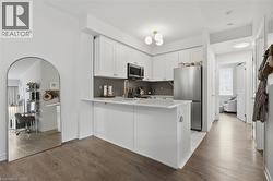 Modern kitchen featuring white cabinetry, stainless steel appliances, a white island, and a tile backsplash - 