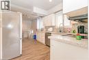 Kitchen featuring white cabinetry, light-toned countertops, tile backsplash, stainless steel appliances, and wood-finish flooring - 574 Upper Sherman Avenue, Hamilton, ON 