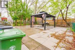 Expansive backyard patio featuring large format pavers, a metal gazebo with a fabric canopy, and mature perimeter trees - 
