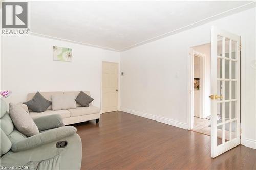 Spacious room featuring wood-finish flooring, white walls, and a white crown molding detail - 574 Upper Sherman Avenue, Hamilton, ON 