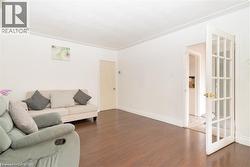 Spacious room featuring wood-finish flooring, white walls, and a white crown molding detail - 
