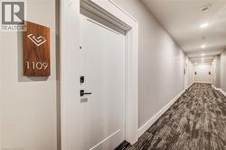 Entry door featuring a contemporary matte black handle and a wood-finish unit number plaque - 