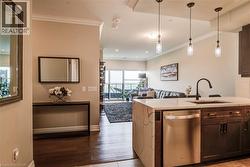 Kitchen island featuring a white countertop with a waterfall edge, dark wood-finish cabinetry, and a stainless steel dishwasher - 