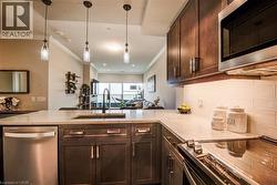 Contemporary kitchen featuring dark wood cabinetry, white stone countertops, and a subway tile backsplash - 
