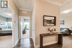 Hallway featuring wood-finish flooring, crown molding, and neutral wall tones - 