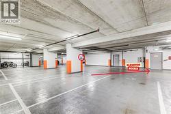 Underground parking garage featuring clearly marked spaces, exposed concrete ceilings, integrated fluorescent lighting, and a dedicated bicycle storage area - 