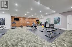 Dedicated fitness area featuring patterned carpet, a wood-paneled accent wall, and recessed lighting - 