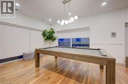 Recreational space featuring a billiard table, wood-finish flooring, and a contemporary chandelier - 
