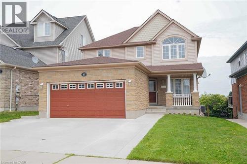 Two-story residence featuring a brick and siding facade, an arched window, a covered front porch with white railings, a two-car garage with a red door, and an asphalt shingle roof - 187 Adler Drive, Cambridge, ON - Outdoor With Facade