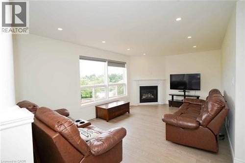 Spacious living area featuring light wood-finish flooring, a white mantel fireplace, and recessed lighting - 187 Adler Drive, Cambridge, ON - Indoor Photo Showing Living Room With Fireplace