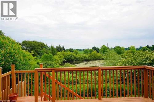 Expansive wood deck with natural wood railing, offering broad views of surrounding verdant trees and a pond - 187 Adler Drive, Cambridge, ON - Outdoor With Deck Patio Veranda With View