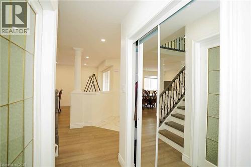 Entryway featuring mirrored closet doors, wood-finish flooring, recessed lighting, and a detailed staircase with an ornate wrought-iron railing - 187 Adler Drive, Cambridge, ON - Indoor Photo Showing Other Room