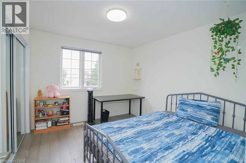 Spacious room featuring wood-finish flooring, a window with exterior views, and a sliding door closet with mirrored panels - 187 Adler Drive, Cambridge, ON - Indoor Photo Showing Bedroom