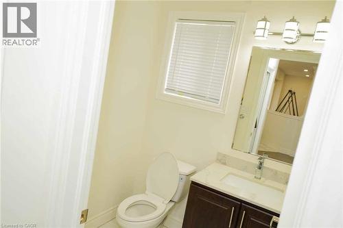 Powder room featuring a single-pane window with horizontal blinds, a dark wood-finish vanity with a quartz countertop, an undermount sink, and a chrome faucet - 187 Adler Drive, Cambridge, ON - Indoor Photo Showing Bathroom