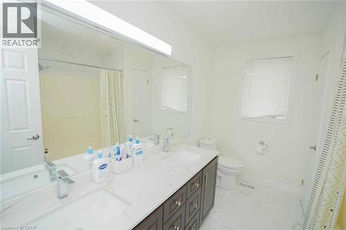 Bright bathroom featuring a double vanity with stone-finish countertop, dual undermount sinks, and polished chrome faucets - 187 Adler Drive, Cambridge, ON - Indoor Photo Showing Bathroom
