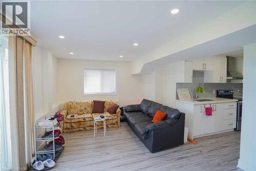 Open-concept living space featuring wood-finish flooring, recessed lighting, and a modern kitchen with white cabinetry, stainless steel appliances, and a tiled backsplash - 187 Adler Drive, Cambridge, ON - Indoor
