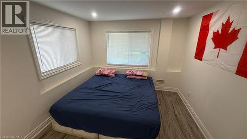 Room featuring wood-finish flooring, two white-framed windows with blinds, and white painted walls - 187 Adler Drive, Cambridge, ON - Indoor Photo Showing Bedroom