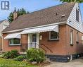 Brick exterior featuring a gabled roof, white window awnings, and an accented foundation - 197 East 12Th Street, Hamilton, ON 