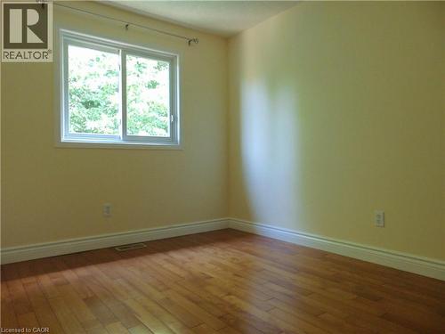 Warm-toned walls complement wood-finish flooring in this room featuring a sliding window - 214 Snowdrop Crescent, Kitchener, ON 