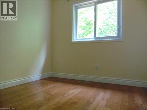 Wood-finish flooring with crisp white baseboards and a sliding window - 214 Snowdrop Crescent, Kitchener, ON 
