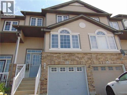 Multi-level townhouse exterior featuring light-toned siding and a stone facade - 214 Snowdrop Crescent, Kitchener, ON 