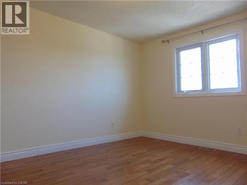 Room with light-toned walls, wood-finish flooring, white baseboards, and a double window with white trim - 214 Snowdrop Crescent, Kitchener, ON 