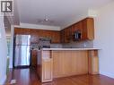 Kitchen featuring wood-finish cabinetry, stainless steel appliances, a tiled backsplash, and a breakfast bar with an integrated storage cabinet - 214 Snowdrop Crescent, Kitchener, ON 