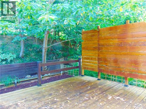 Expansive outdoor decking featuring a privacy screen, perimeter railing, and integrated landscaping with mature trees - 214 Snowdrop Crescent, Kitchener, ON 