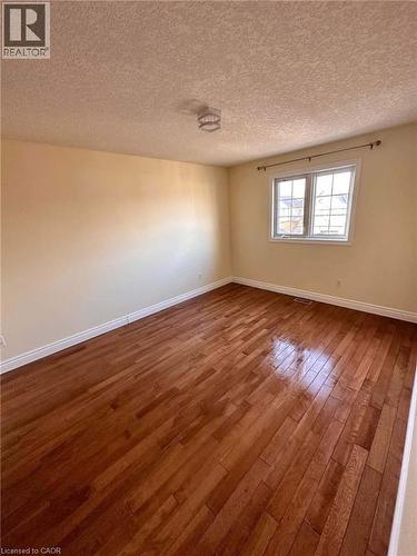 Spacious bedroom featuring rich wood-finish flooring, light-toned walls, and a large window with natural light - 214 Snowdrop Crescent, Kitchener, ON 