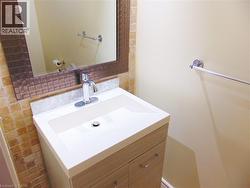 Vanity featuring a white integrated sink and countertop, wood-finish cabinetry, and chrome fixtures - 