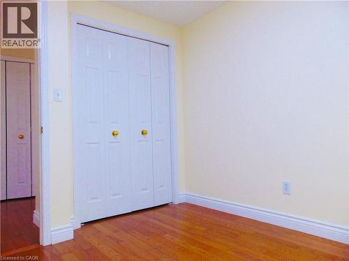 Bedroom featuring wood-finish flooring, white baseboards, and light yellow walls - 214 Snowdrop Crescent, Kitchener, ON 