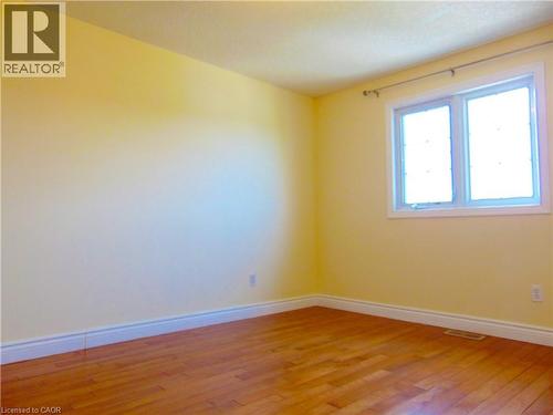 Bright beroom room featuring a double window, wood-finish flooring, and white baseboards - 214 Snowdrop Crescent, Kitchener, ON 