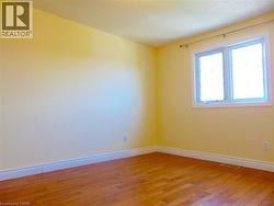 Bright bedroom featuring a double window, wood-finish flooring, and white baseboards - 