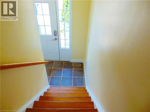 Entryway featuring a white paneled door with glass inserts, patterned floor tiling, and a wooden handrail - 214 Snowdrop Crescent, Kitchener, ON 